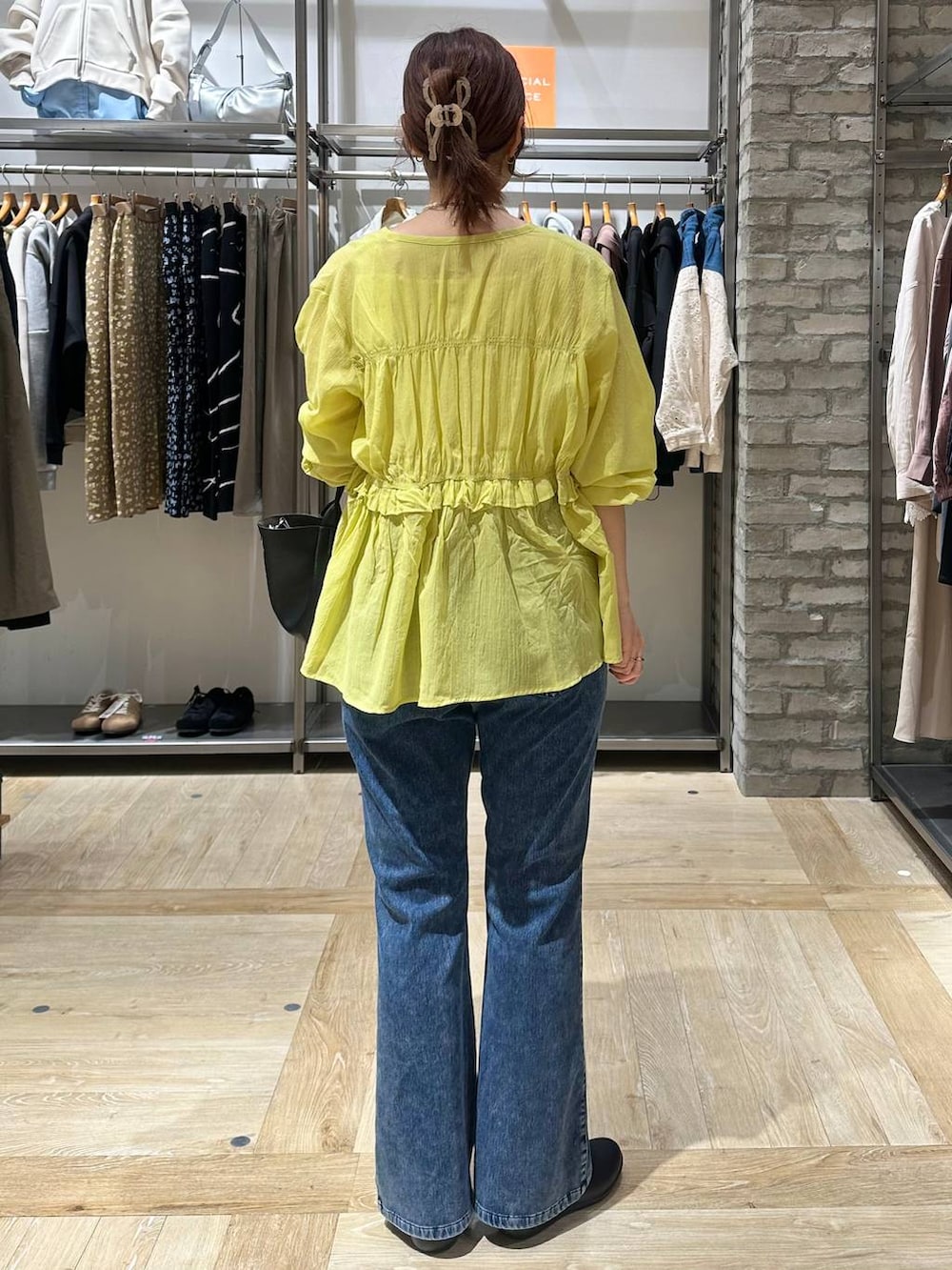 ブラック系のパンプス、ブラック系のトートバッグ、ブルー系のデニムパンツを着用したレディースの春コーディネートの3枚目の写真