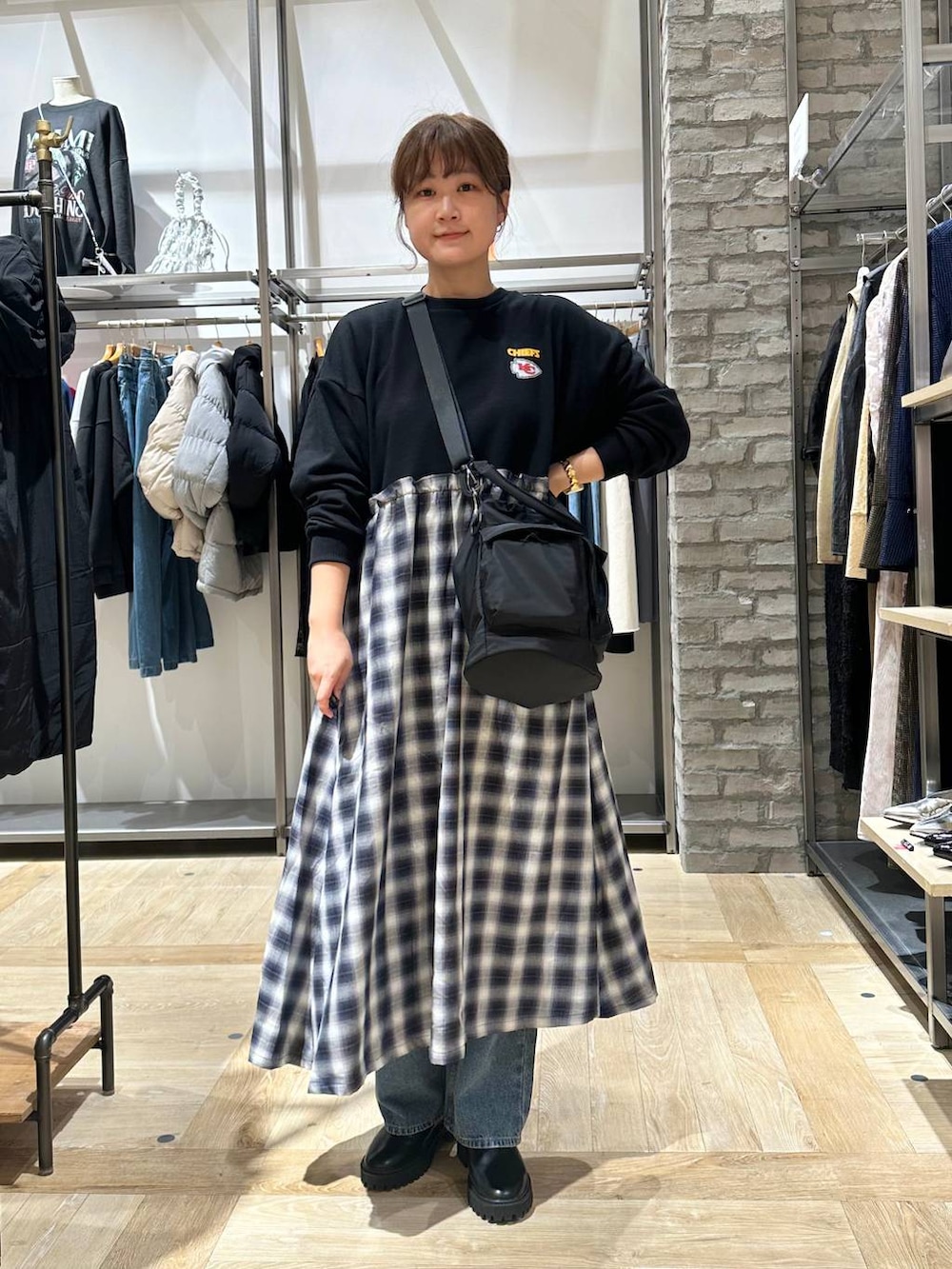 ブラック系のショルダーバッグ、ブルー系のデニムパンツ、ベージュ系のダウンベストを着用したレディースの秋コーディネートの5枚目の写真