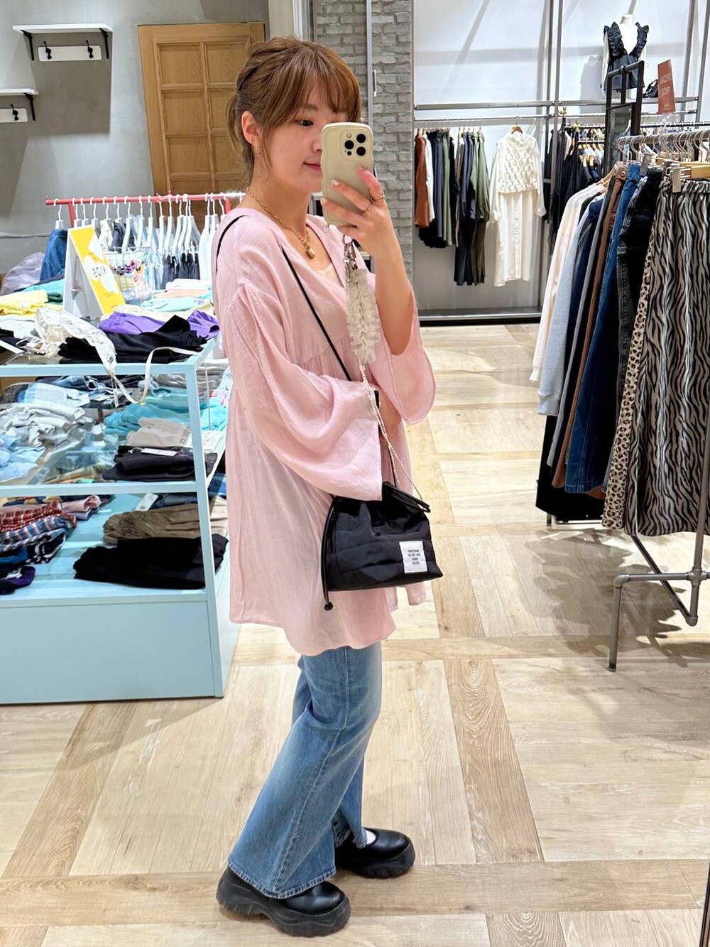 ブラック系のスニーカー、ホワイト系のタンクトップ、ブルー系のデニムパンツを着用したレディースの春コーディネートの3枚目の写真