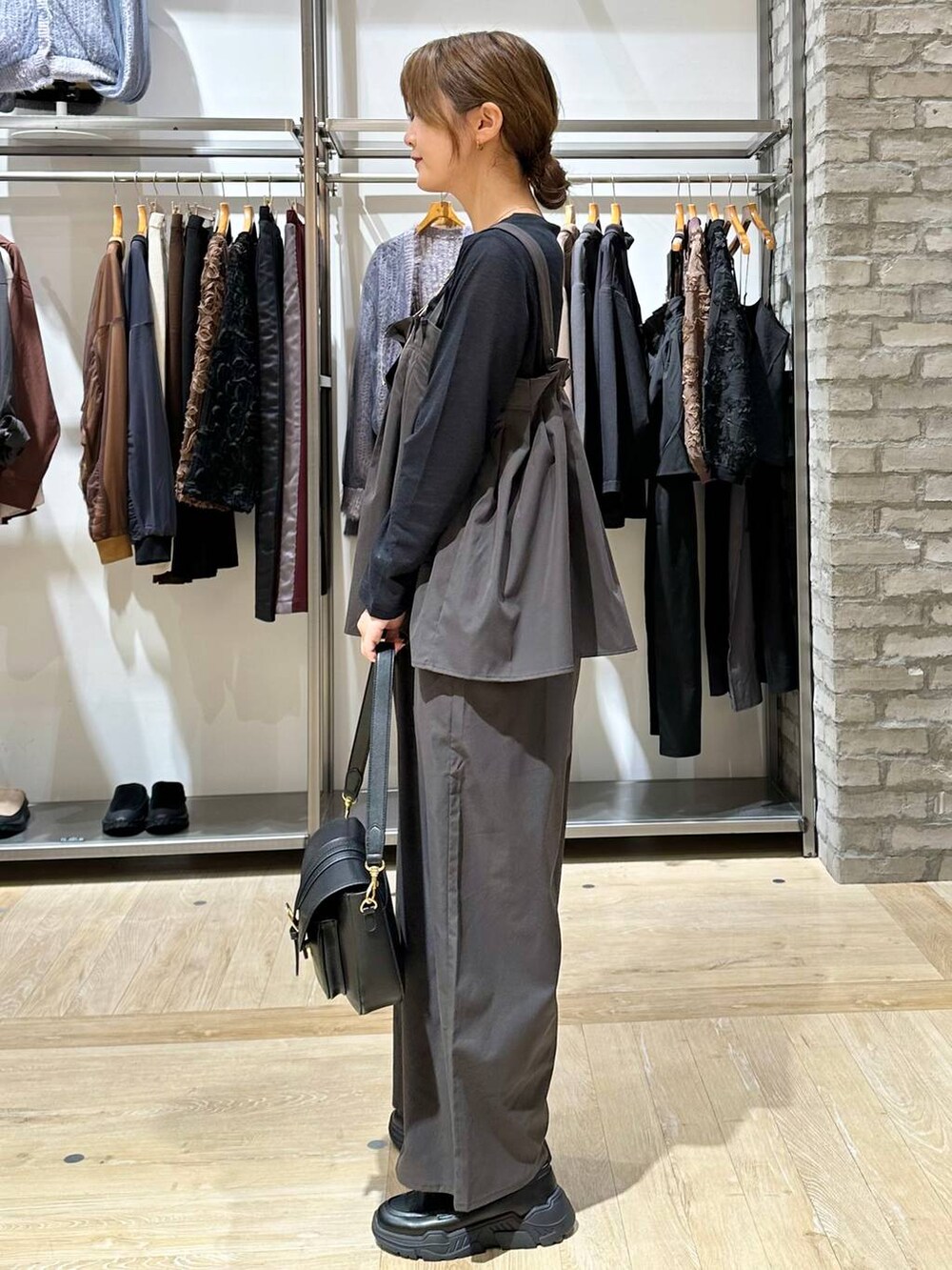 ブラック系のスニーカー、ブラック系のショルダーバッグ、グレー系のサロペット/オーバーオールを着用したレディースの秋コーディネートの3枚目の写真