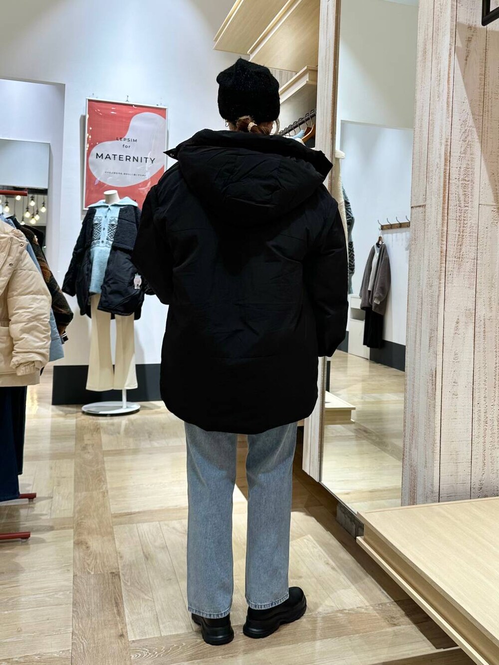 ブラック系のダウンジャケット/コート、ブルー系のデニムパンツ、ブラック系のブーツを着用したレディースの冬コーディネートの4枚目の写真