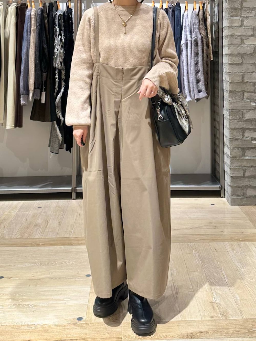 ベージュ系のニット/セーター、ブラック系のボストンバッグ、ブラック系のブーツを着用したレディースの秋コーディネートの6枚目の写真