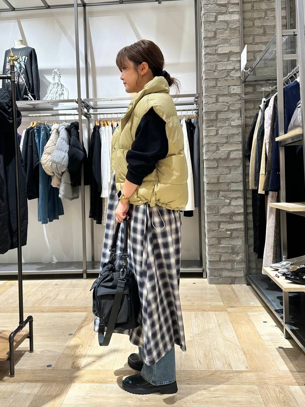 ブラック系のショルダーバッグ、ブルー系のデニムパンツ、ベージュ系のダウンベストを着用したレディースの秋コーディネートの3枚目の写真
