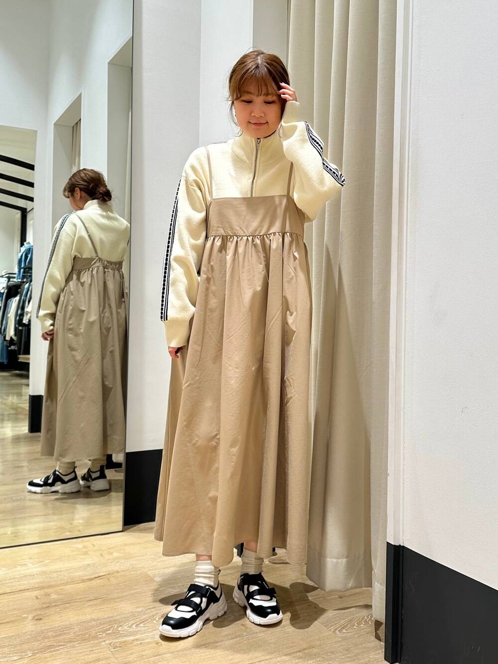 ベージュ系のワンピース、ブラック系のその他アウター、ホワイト系のスニーカーを着用したレディースの冬コーディネートの5枚目の写真