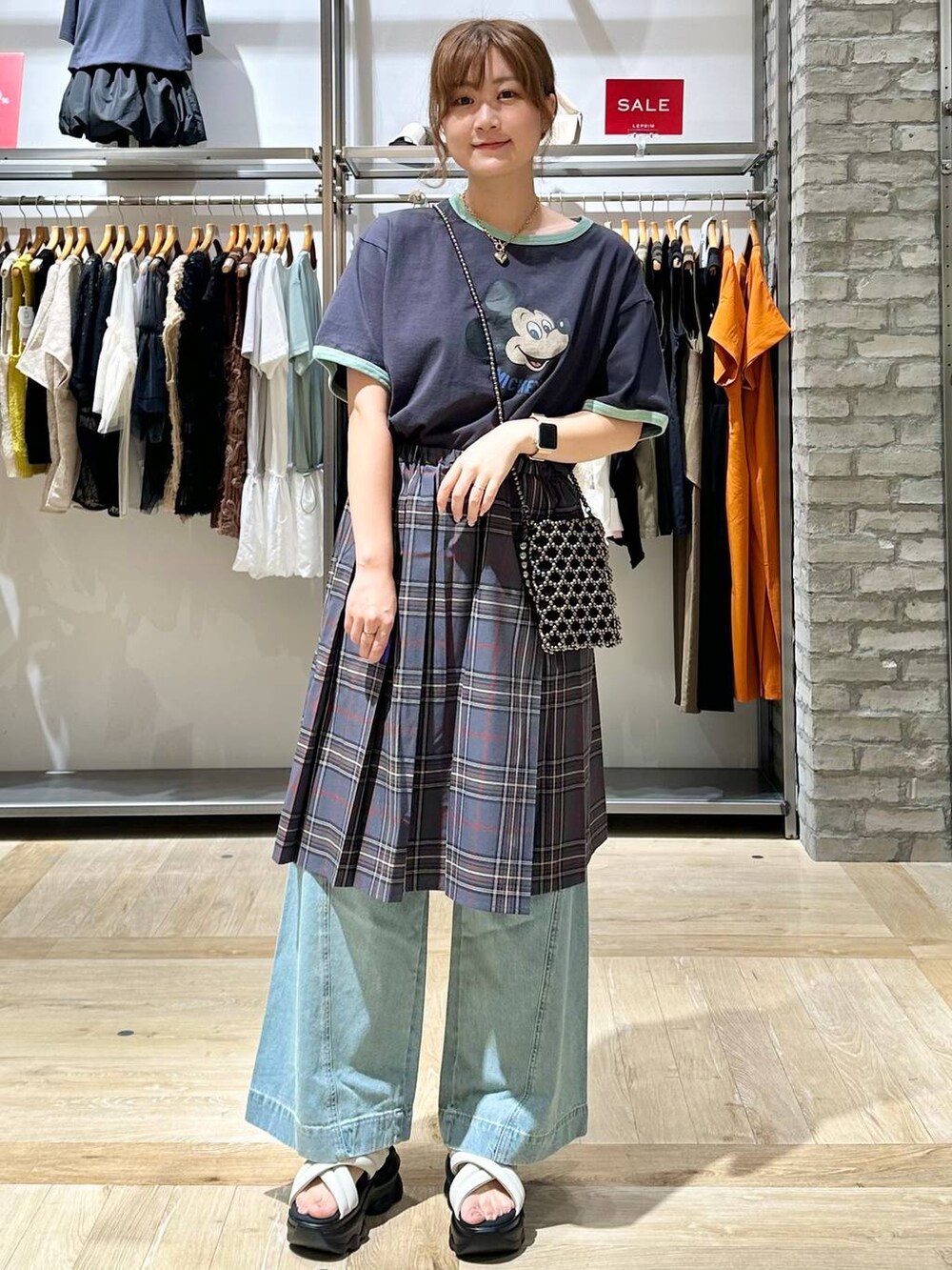 ブルー系のデニムパンツ、シルバー系のショルダーバッグ、ホワイト系のサンダルを着用したレディースの夏コーディネートの2枚目の写真