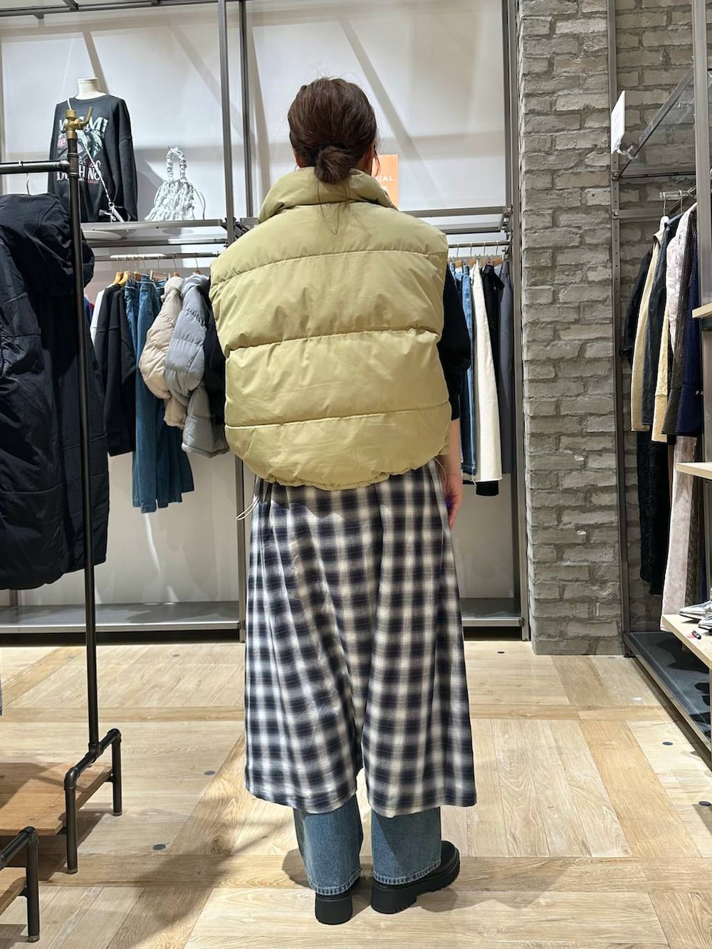ブラック系のショルダーバッグ、ブルー系のデニムパンツ、ベージュ系のダウンベストを着用したレディースの秋コーディネートの4枚目の写真