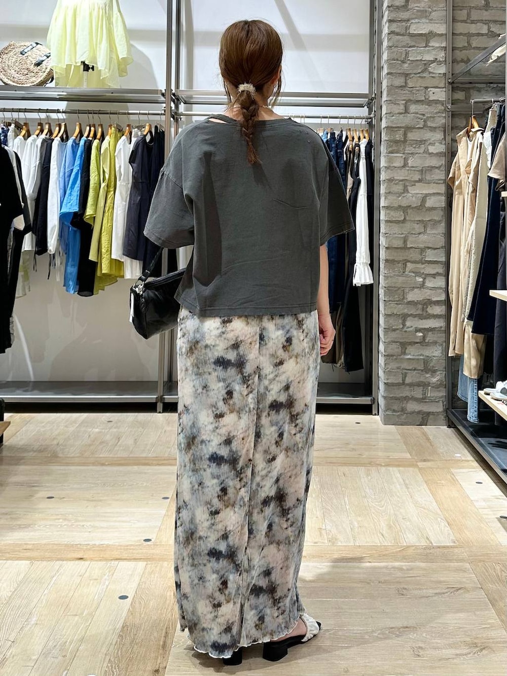 ブラック系のハンドバッグ、ホワイト系のサンダル、グレー系のTシャツ/カットソーを着用したレディースの夏コーディネートの3枚目の写真