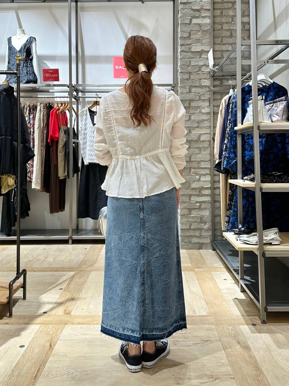 シルバー系のボストンバッグ、ブルー系のデニムスカート、ホワイト系のシャツ/ブラウスを着用したレディースの夏コーディネートの3枚目の写真