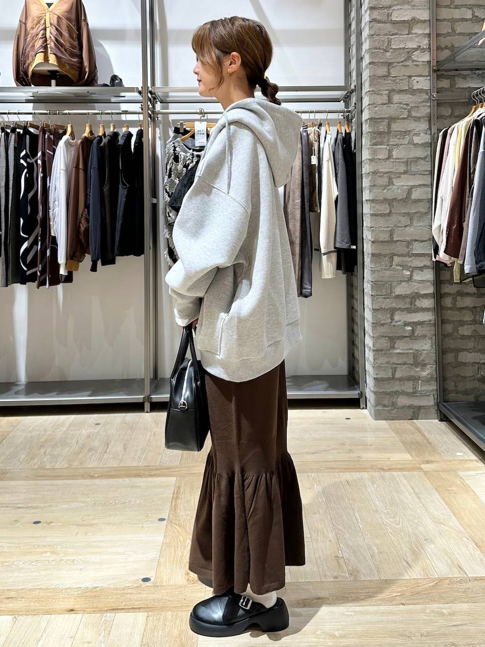 ブラウン系のスカート、ホワイト系のTシャツ/カットソー、ブラック系のサンダルを着用したレディースの秋コーディネートの3枚目の写真