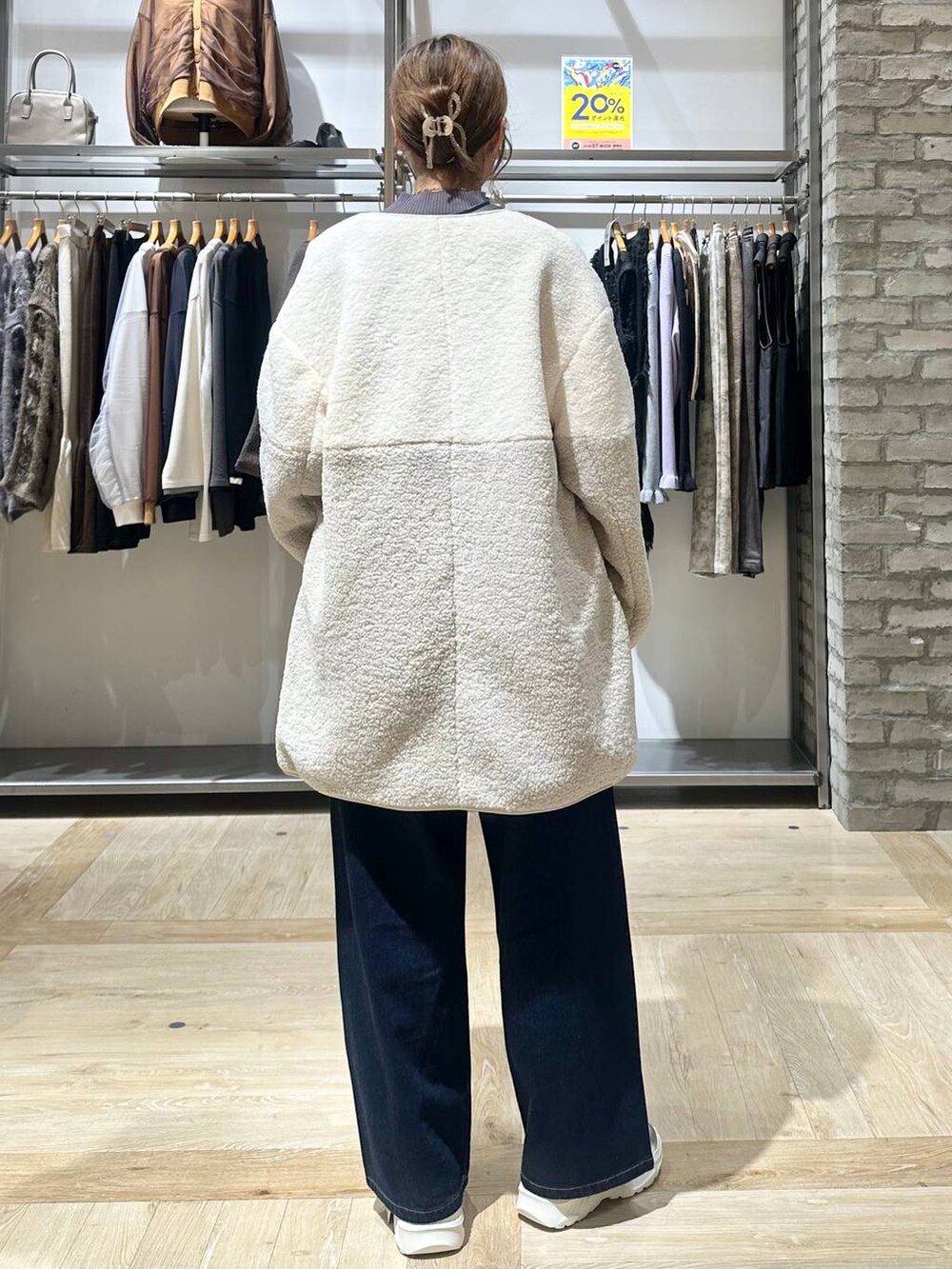 ブルー系のデニムパンツ、グレー系のニット/セーター、ホワイト系のスニーカーを着用したレディースの秋コーディネートの4枚目の写真