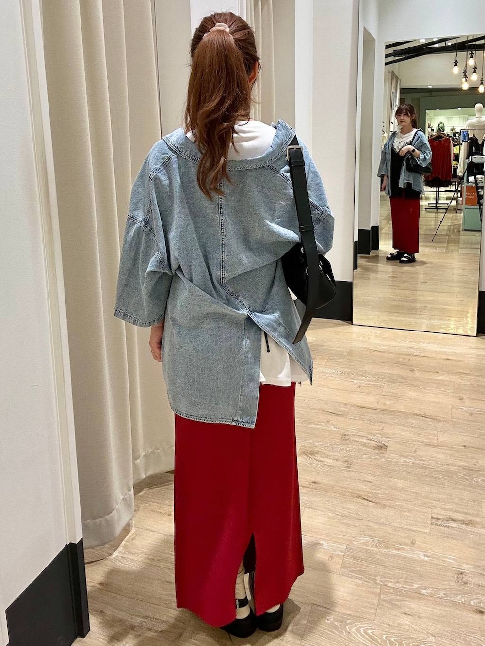 レッド系のスカート、ブラック系のショルダーバッグ、ブラック系のサンダルを着用したレディースの春コーディネートの3枚目の写真