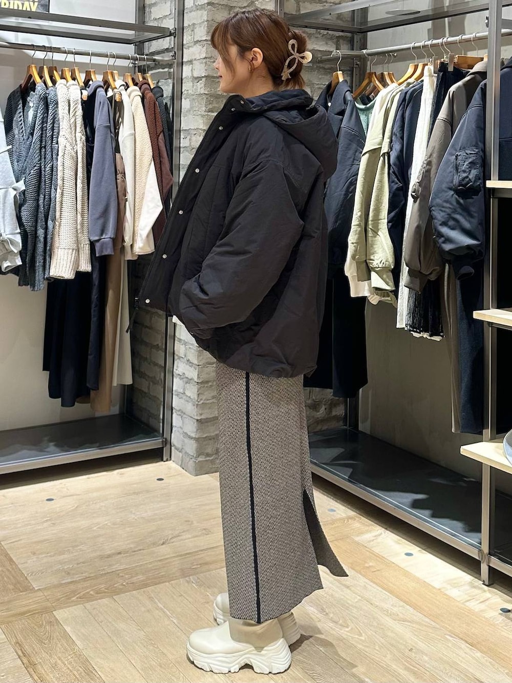 ホワイト系のブーツ、ブラック系のスカート、ブラック系のその他アウターを着用したレディースの冬コーディネートの2枚目の写真