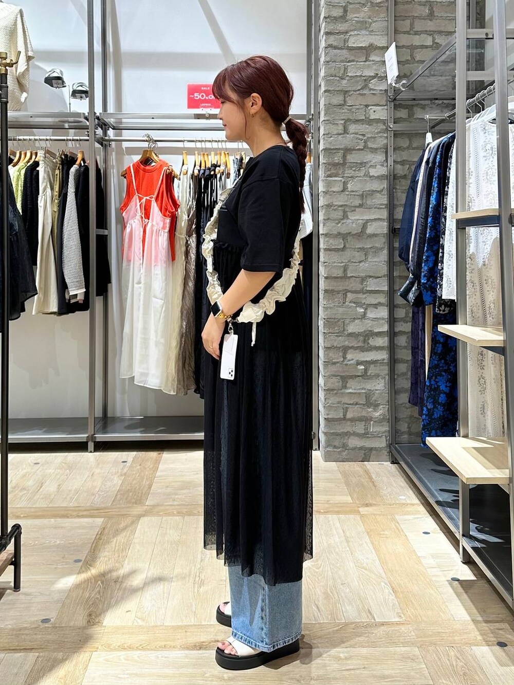 ブルー系のデニムパンツ、ホワイト系のサンダル、ブラック系のワンピースを着用したレディースの夏コーディネートの2枚目の写真