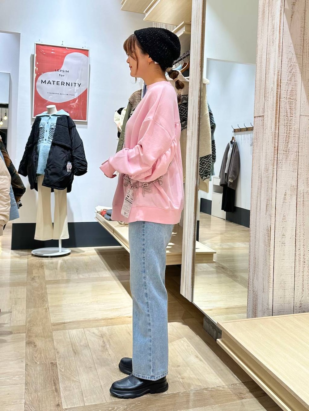 ブルー系のデニムパンツ、ブラック系のブーツ、ピンク系のスウェットを着用したレディースの冬コーディネートの3枚目の写真