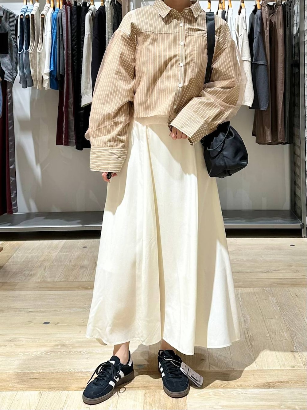 ブラック系のショルダーバッグ、ホワイト系のスカート、イエロー系のシャツ/ブラウスを着用したレディースの秋コーディネートの5枚目の写真