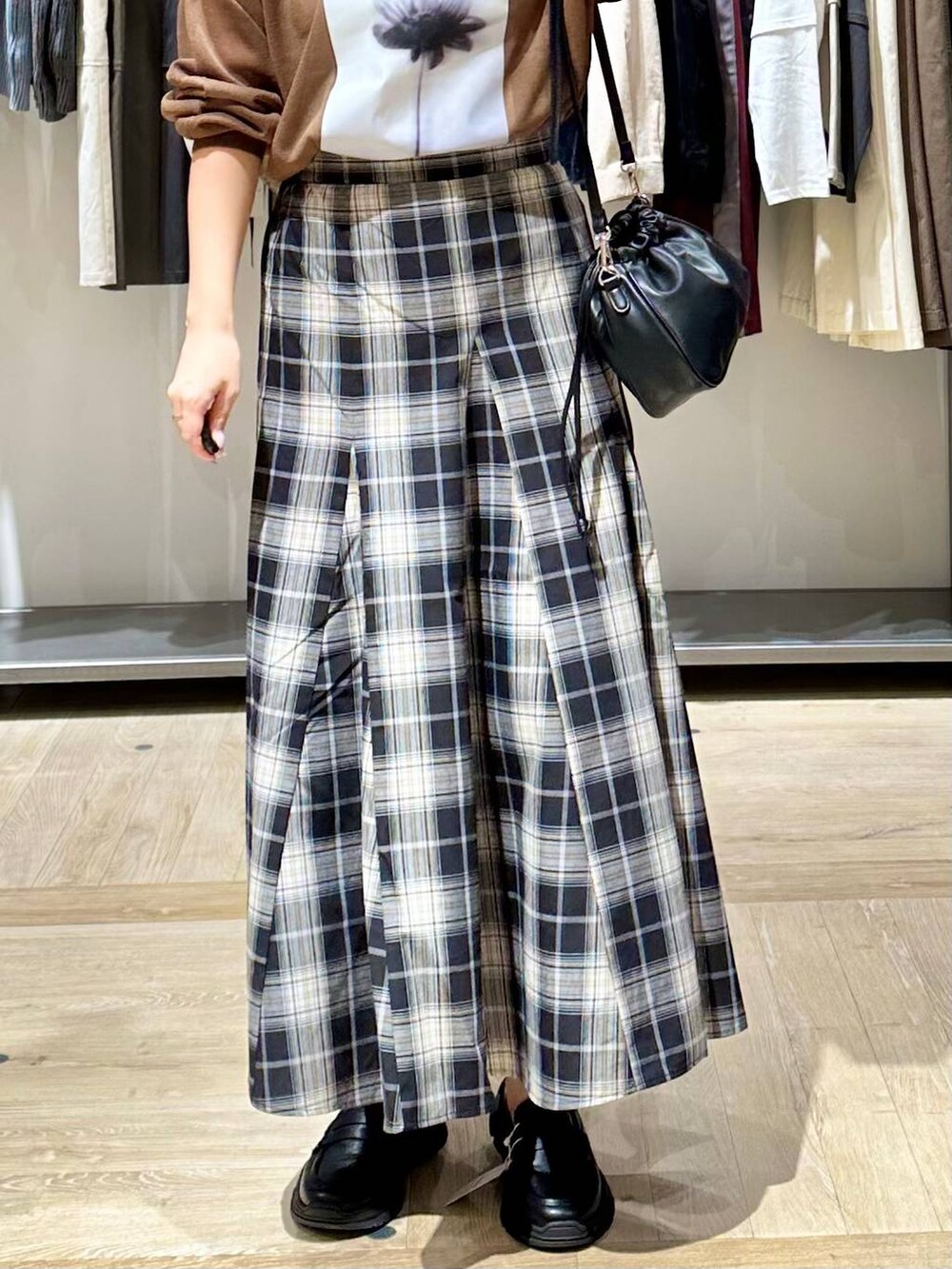 ブラウン系のニット/セーター、ブラック系のスカート、ブラック系のスニーカーを着用したレディースの秋コーディネートの5枚目の写真