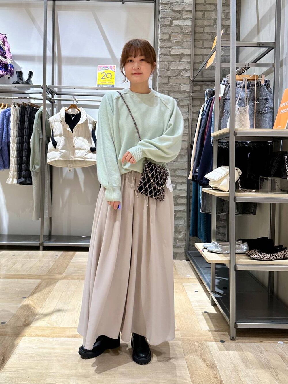 グリーン系のニット/セーター、ブラック系のブーツ、ホワイト系のブルゾンを着用したレディースの秋コーディネートの4枚目の写真