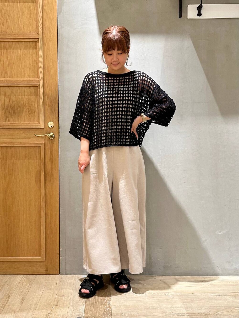 ベージュ系のその他パンツ、ブラック系のニット/セーター、ブラック系のサンダルを着用したレディースの春コーディネートの2枚目の写真
