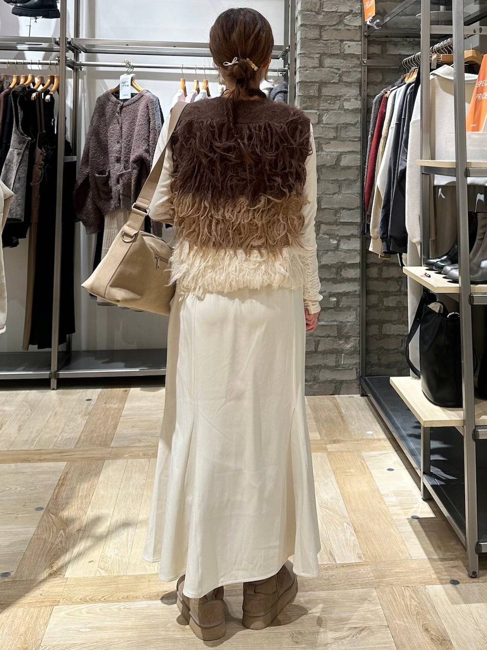 ベージュ系のショルダーバッグ、ベージュ系のブーツ、ブラウン系のベストを着用したレディースの冬コーディネートの3枚目の写真