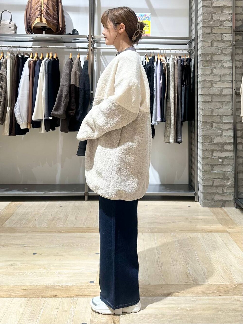 ブルー系のデニムパンツ、グレー系のニット/セーター、ホワイト系のスニーカーを着用したレディースの秋コーディネートの3枚目の写真