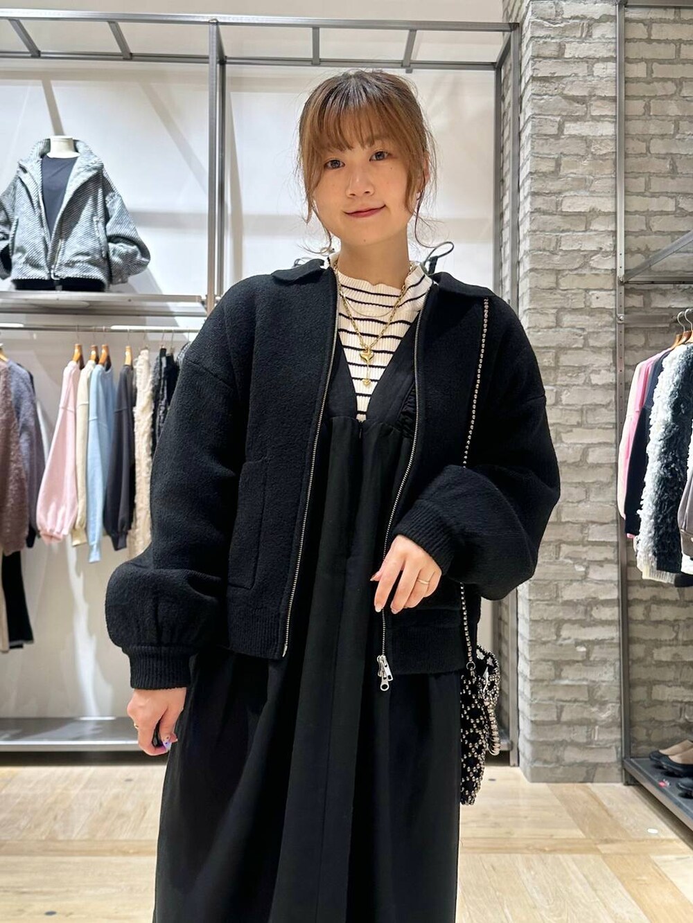 ブラック系のショルダーバッグ、ホワイト系のニット/セーター、ブラック系のブーツを着用したレディースの秋コーディネートの5枚目の写真