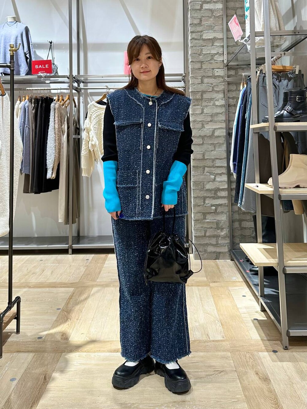 ブラック系のスニーカー、ブルー系のベスト、ブルー系のデニムパンツを着用したレディースの冬コーディネートの2枚目の写真