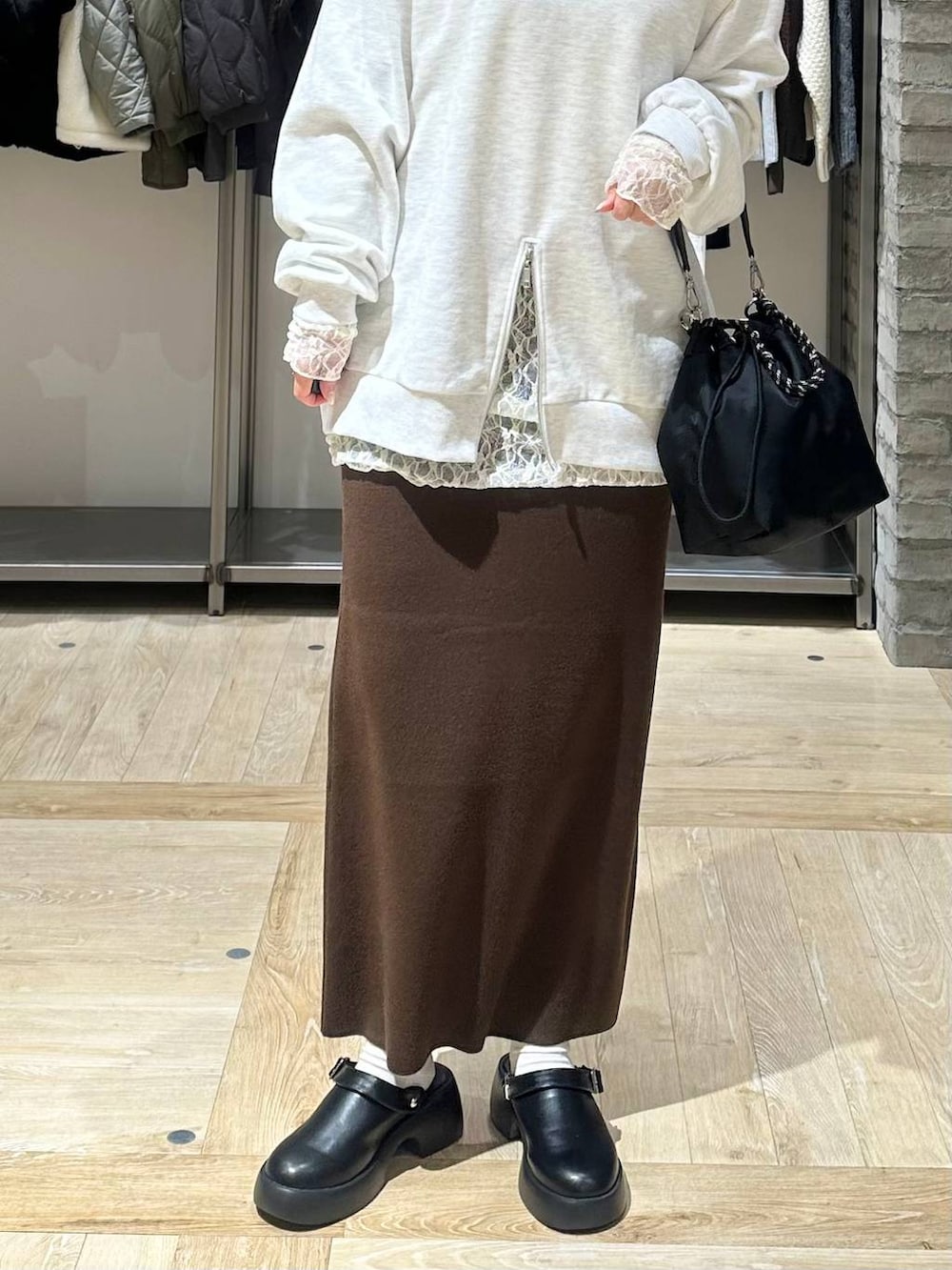 ブラック系のショルダーバッグ、ブラウン系のスカート、ブラック系のサンダルを着用したレディースの冬コーディネートの4枚目の写真