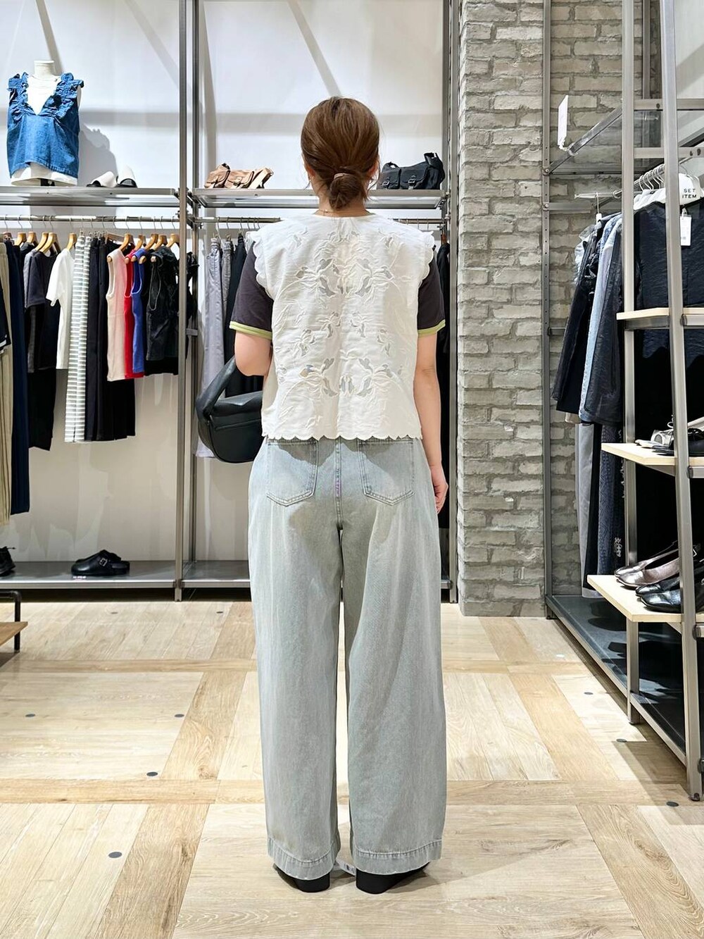 ホワイト系のサンダル、ホワイト系のベスト、ブルー系のデニムパンツを着用したレディースの春コーディネートの3枚目の写真