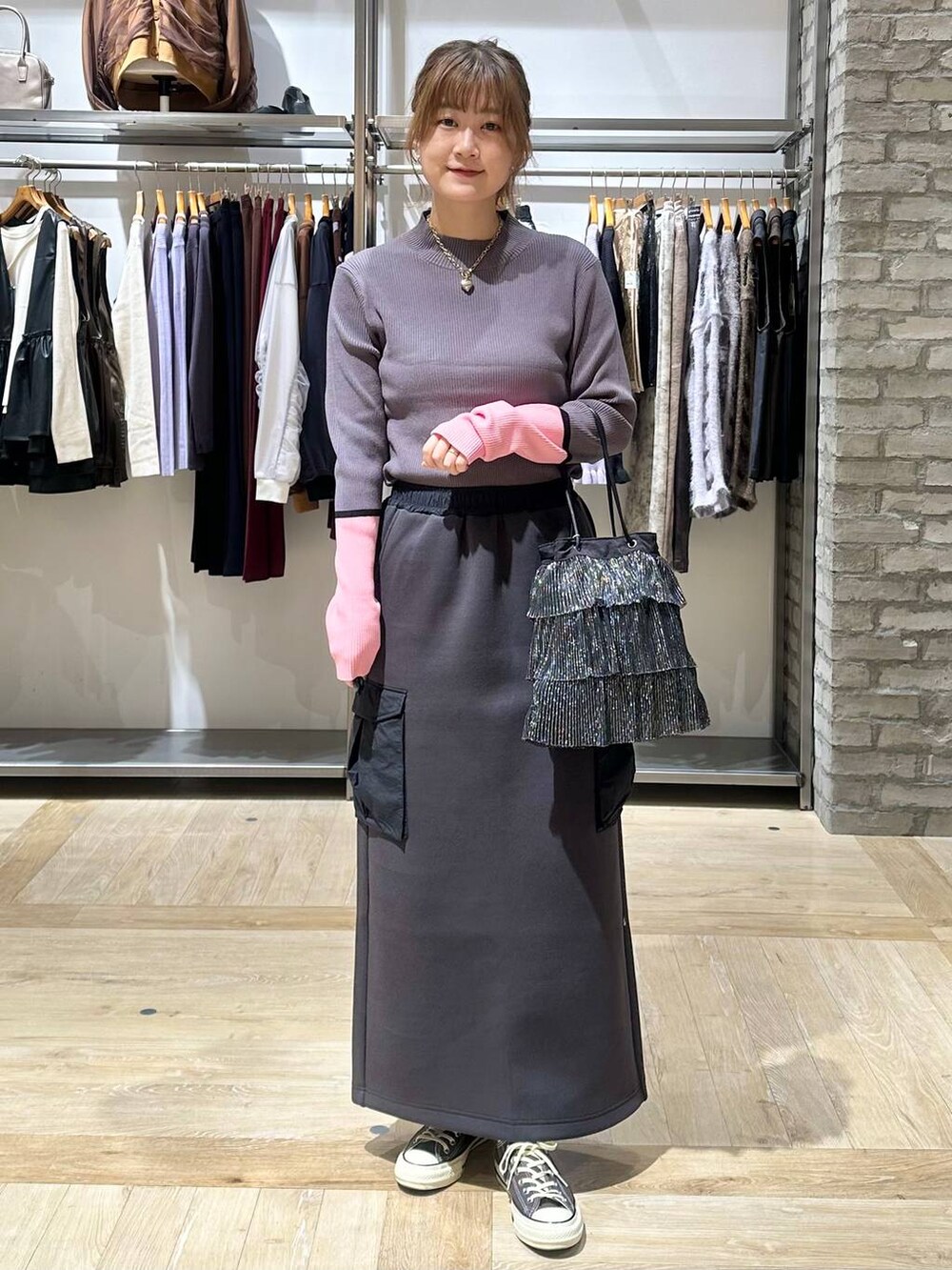 グレー系のニット/セーター、イエロー系のスニーカー、ブラック系のショルダーバッグを着用したレディースの秋コーディネートの2枚目の写真