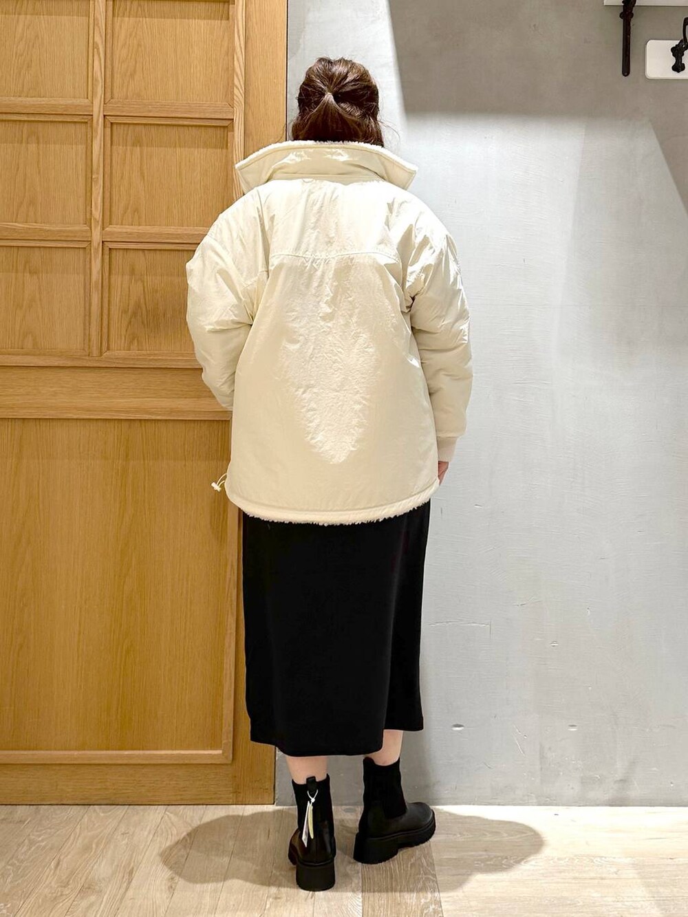 ブラック系のワンピース、ブラック系のブーツ、シルバー系のトートバッグを着用したレディースの冬コーディネートの6枚目の写真