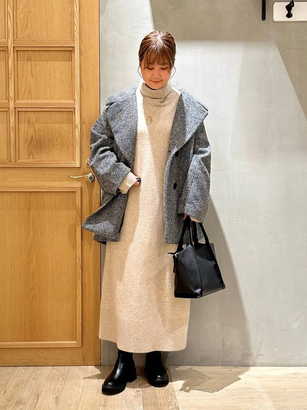 ブラック系のショルダーバッグ、ブラック系のブーツ、ベージュ系のワンピースを着用したレディースの冬コーディネートの6枚目の写真