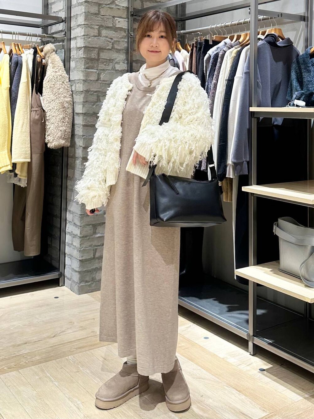 ホワイト系のTシャツ/カットソー、ブラック系のショルダーバッグ、ホワイト系のニット/セーターを着用したレディースの冬コーディネートの2枚目の写真