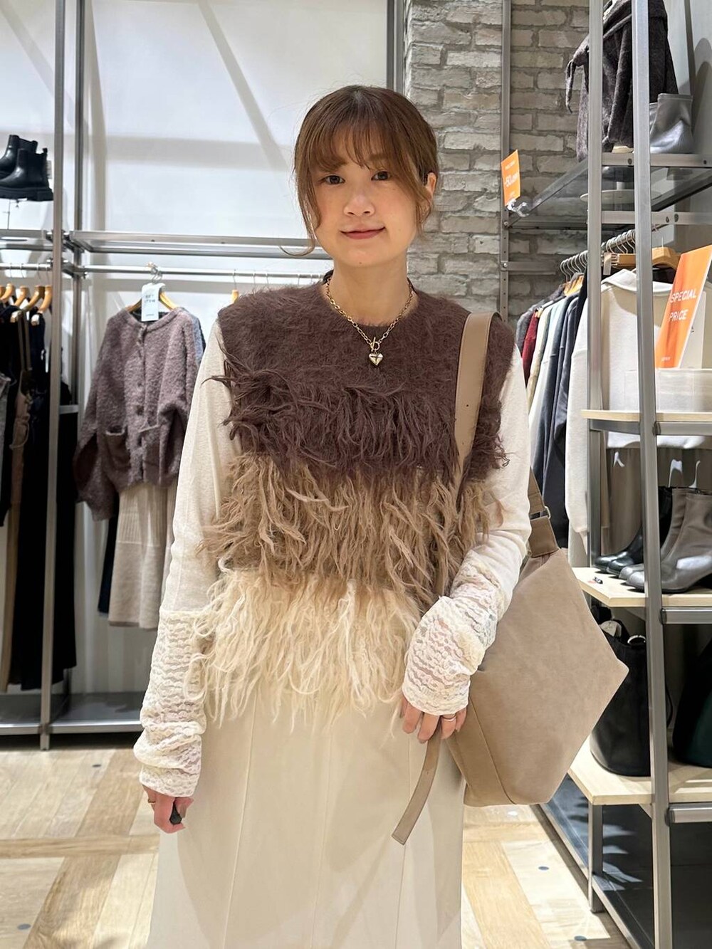 ベージュ系のショルダーバッグ、ベージュ系のブーツ、ブラウン系のベストを着用したレディースの冬コーディネートの4枚目の写真