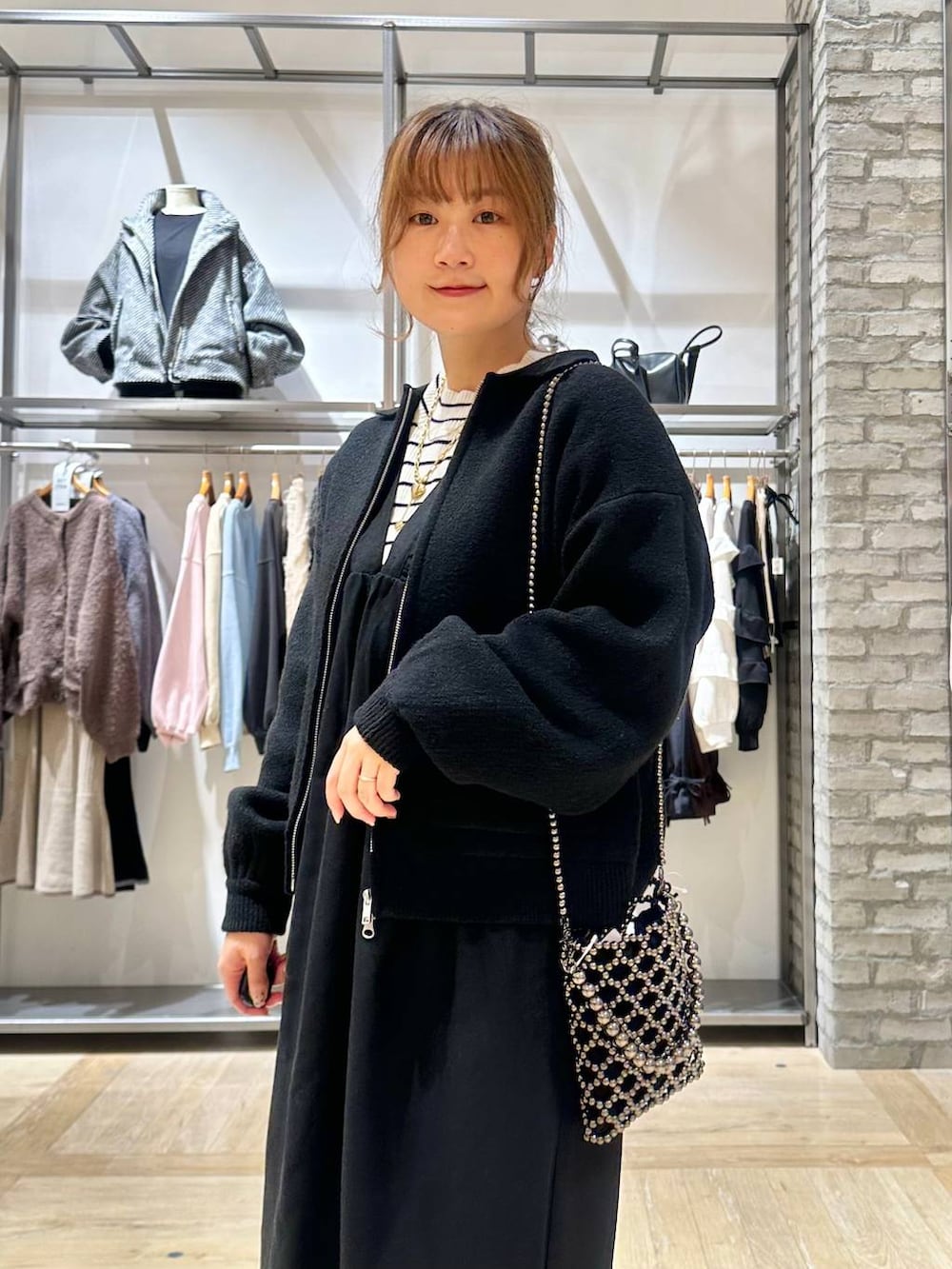 ブラック系のショルダーバッグ、ホワイト系のニット/セーター、ブラック系のブーツを着用したレディースの秋コーディネートの6枚目の写真