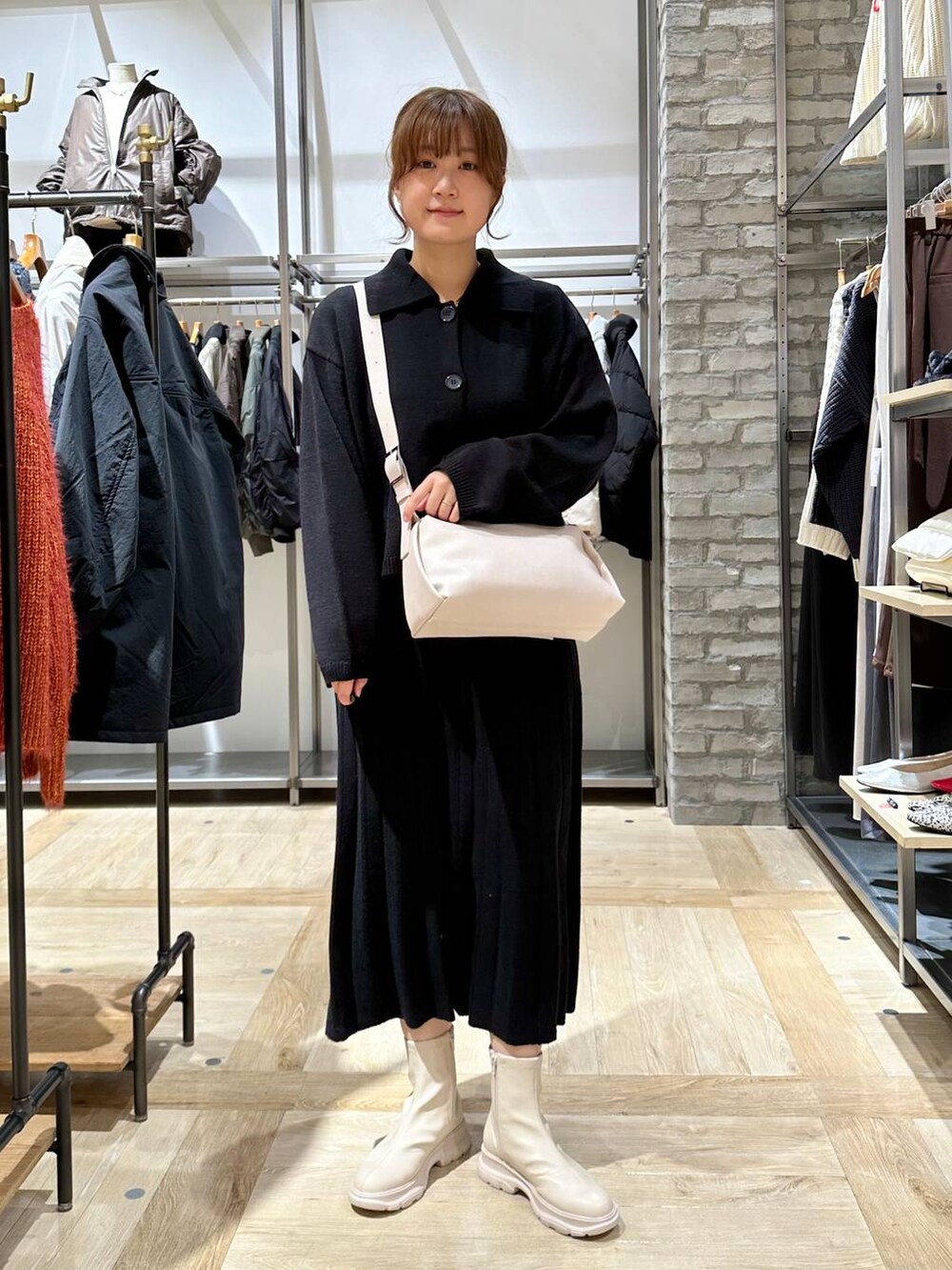 ホワイト系のブーツ、ホワイト系のショルダーバッグ、ブラック系のワンピースを着用したレディースの秋コーディネートの2枚目の写真