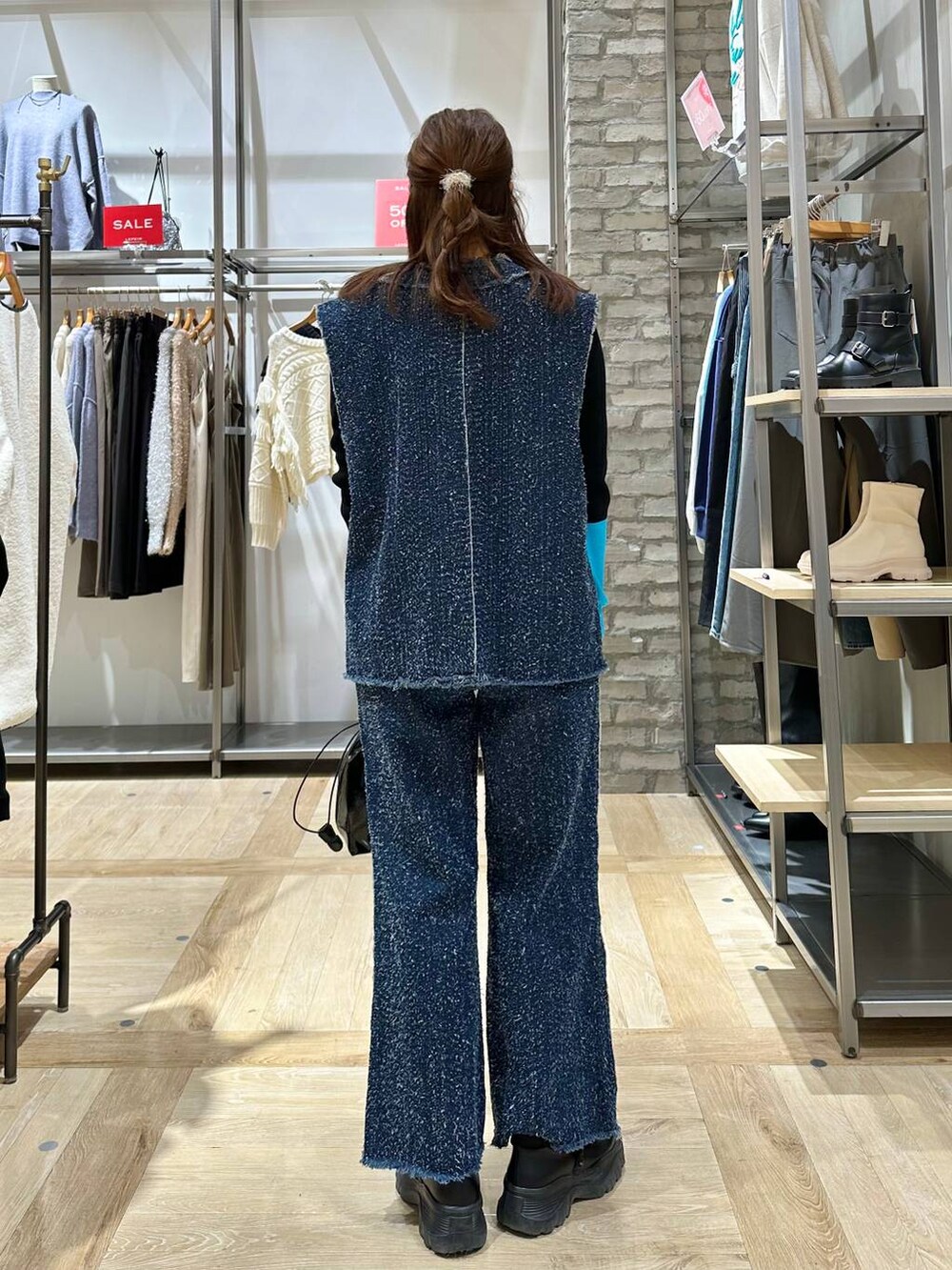 ブラック系のスニーカー、ブルー系のベスト、ブルー系のデニムパンツを着用したレディースの冬コーディネートの4枚目の写真