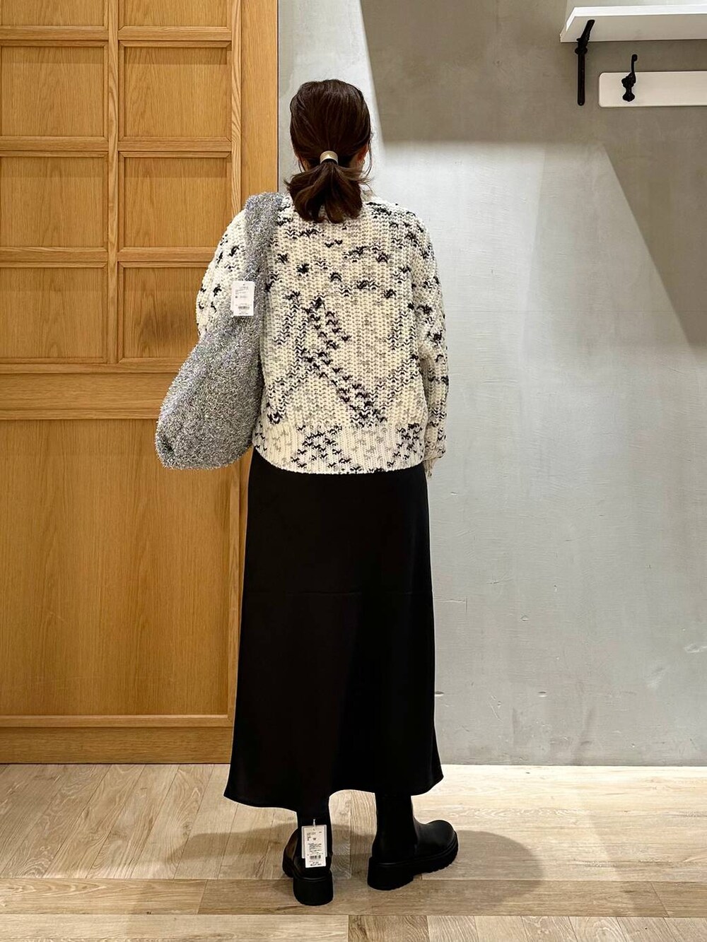 シルバー系のショルダーバッグ、ブラック系のスカート、ブラック系のブーツを着用したレディースの秋コーディネートの4枚目の写真