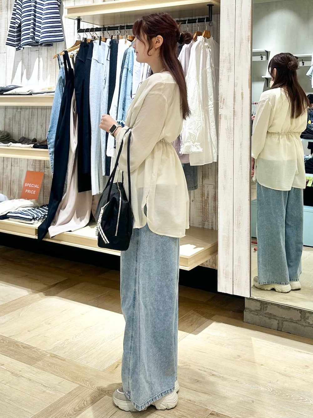 ブルー系のデニムパンツ、ブラック系のボストンバッグ、ホワイト系のシャツ/ブラウスを着用したレディースの春コーディネートの2枚目の写真