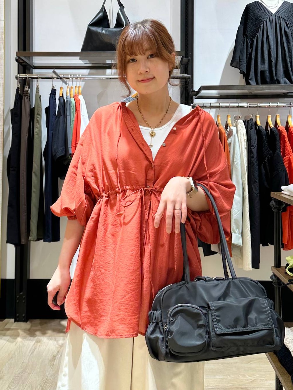 ブラック系のパンプス、オレンジ系のシャツ/ブラウス、グレー系のボストンバッグを着用したレディースの春コーディネートの4枚目の写真