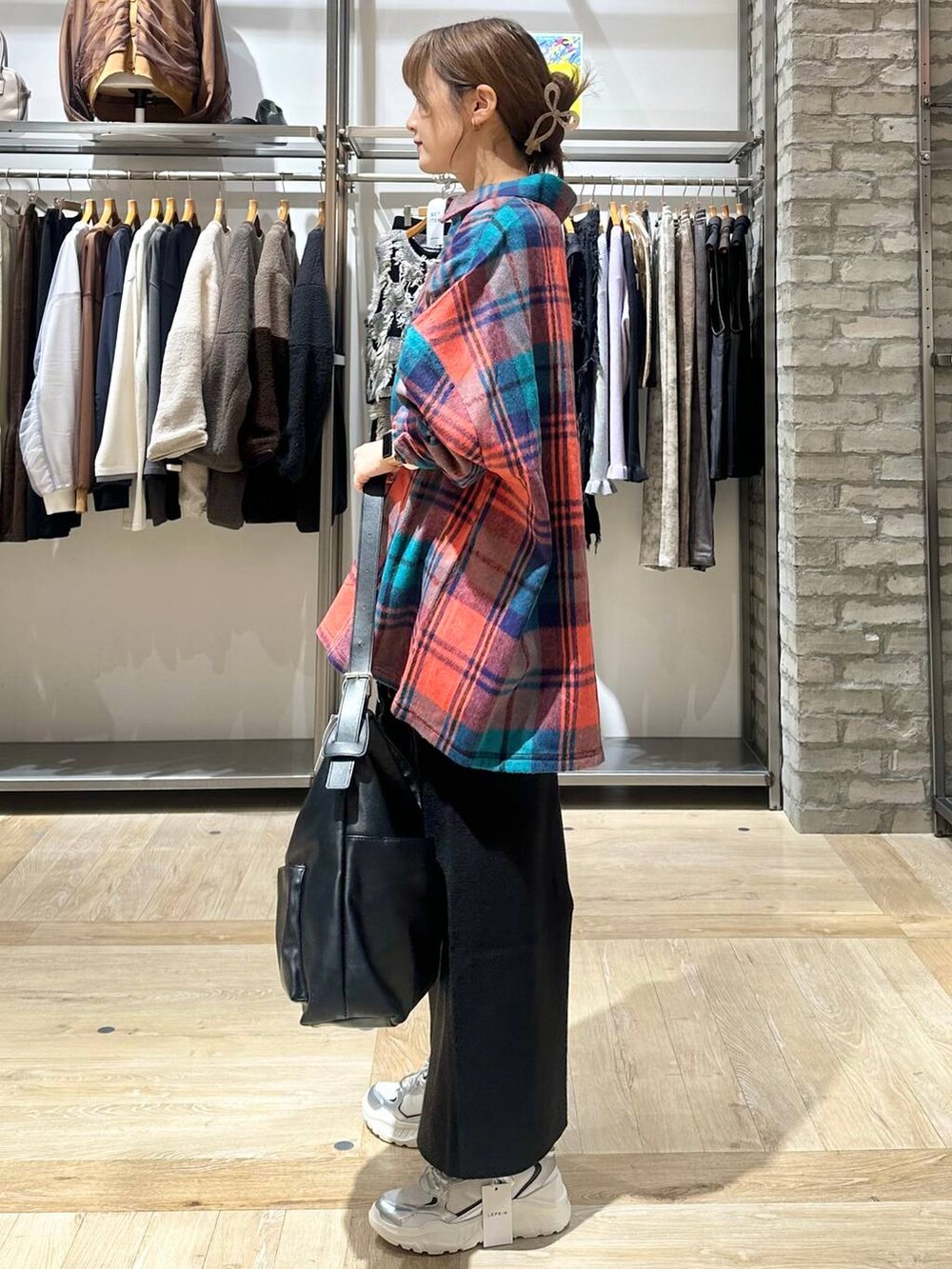 ブラック系のスカート、ホワイト系のスニーカー、ブラック系のショルダーバッグを着用したレディースの秋コーディネートの2枚目の写真