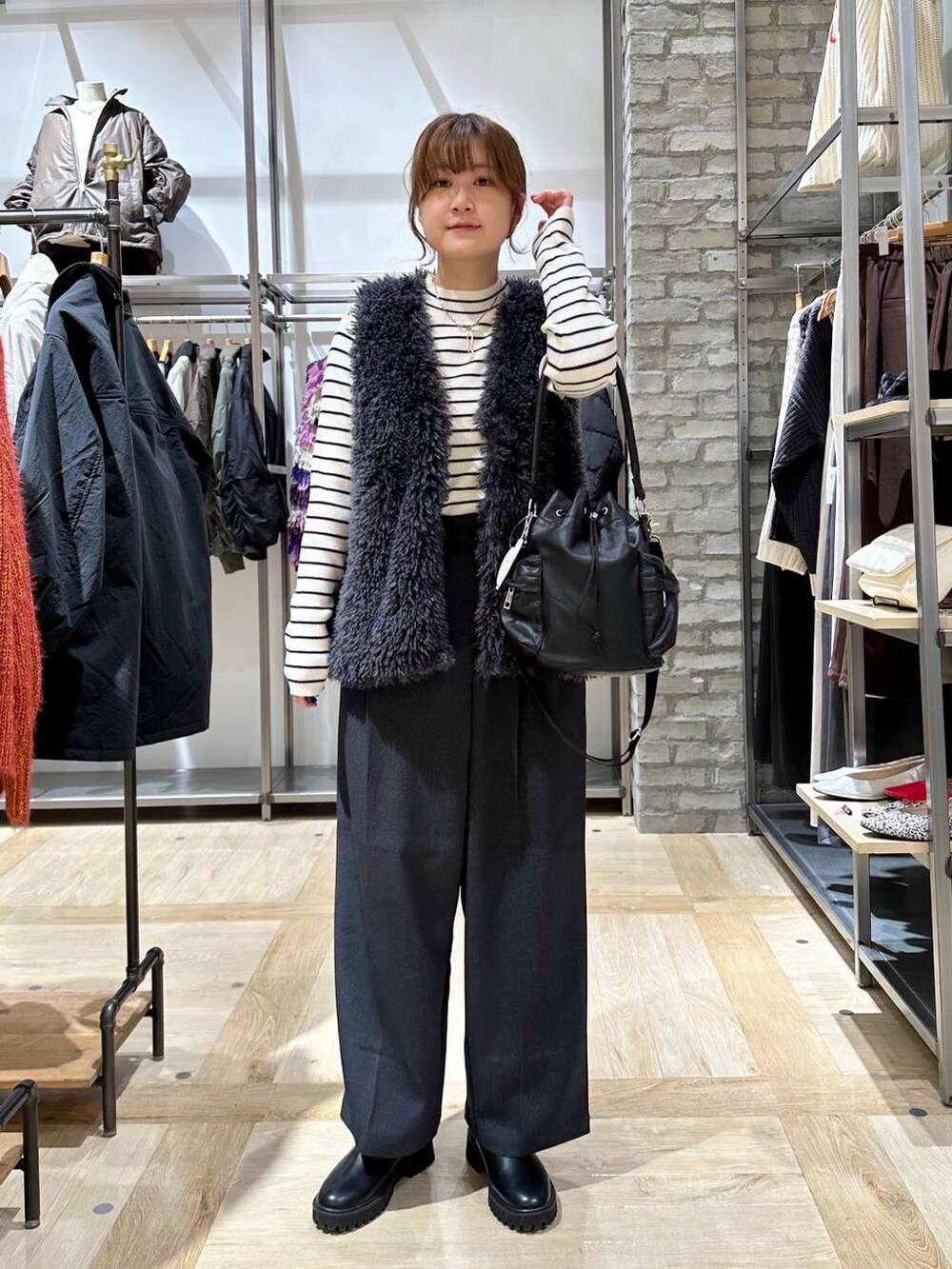 ブラック系のブーツ、ホワイト系のニット/セーター、ブラック系のショルダーバッグを着用したレディースの秋コーディネートの2枚目の写真