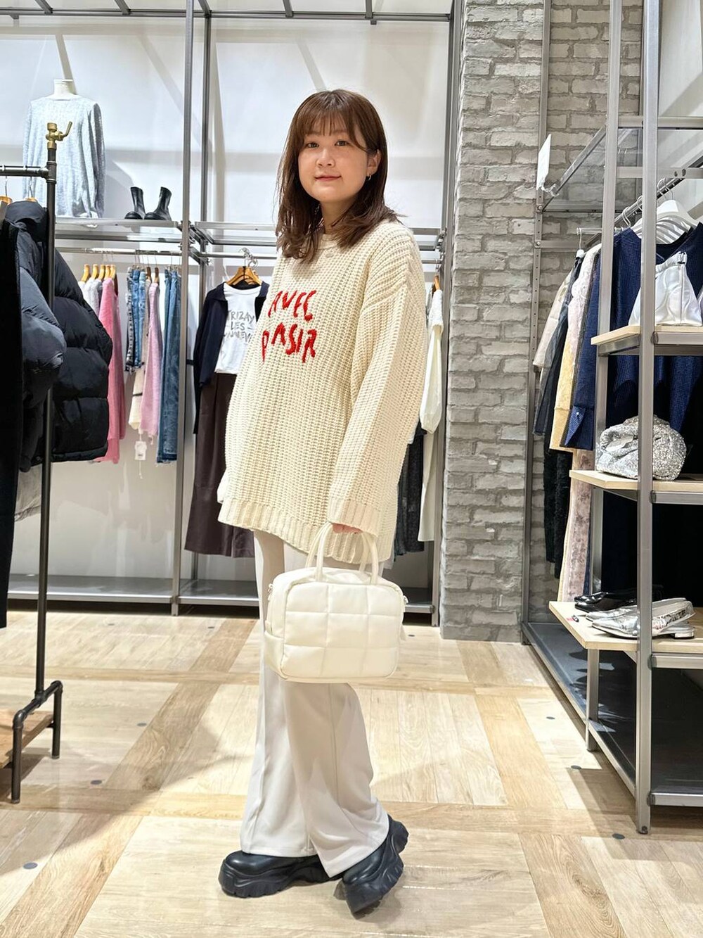 ホワイト系のボストンバッグ、ブラック系のスニーカー、ホワイト系のニット/セーターを着用したレディースの秋コーディネートの2枚目の写真