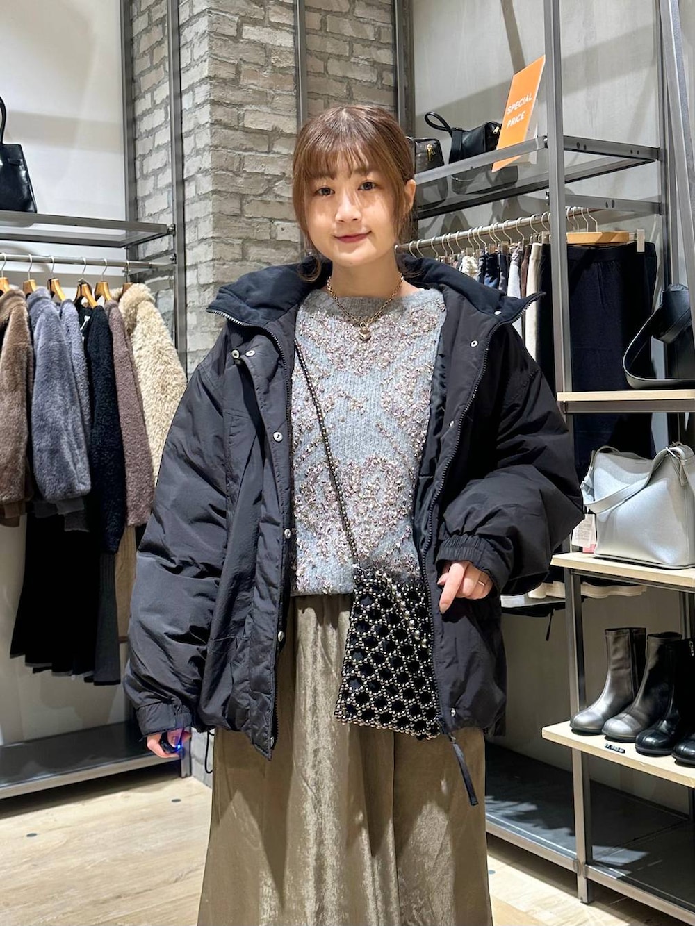 ブラック系のショルダーバッグ、ブラック系のその他アウター、ブラウン系のスカートを着用したレディースの秋コーディネートの7枚目の写真