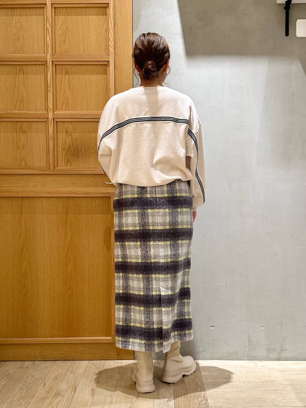 グレー系のスカート、ブラック系のショルダーバッグ、ホワイト系のブーツを着用したレディースの冬コーディネートの4枚目の写真