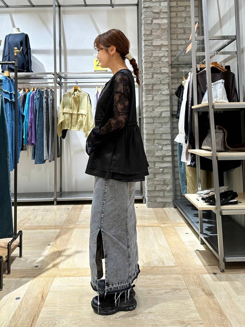 グレー系のスカート、ブラック系のスニーカー、ブラック系のTシャツ/カットソーを着用したレディースの秋コーディネートの2枚目の写真