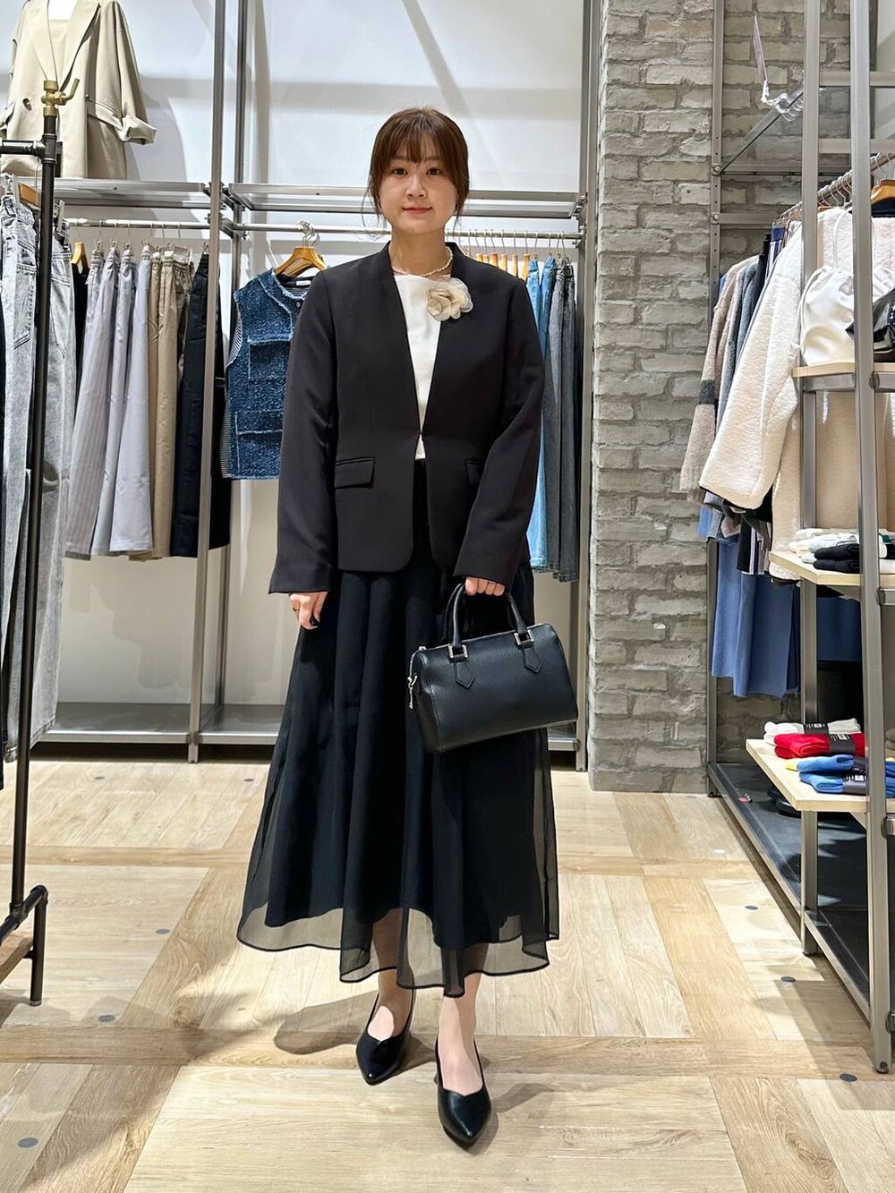 ブラック系のスカート、ブラック系のスーツジャケット、ホワイト系のTシャツ/カットソーを着用したレディースの冬コーディネートの2枚目の写真