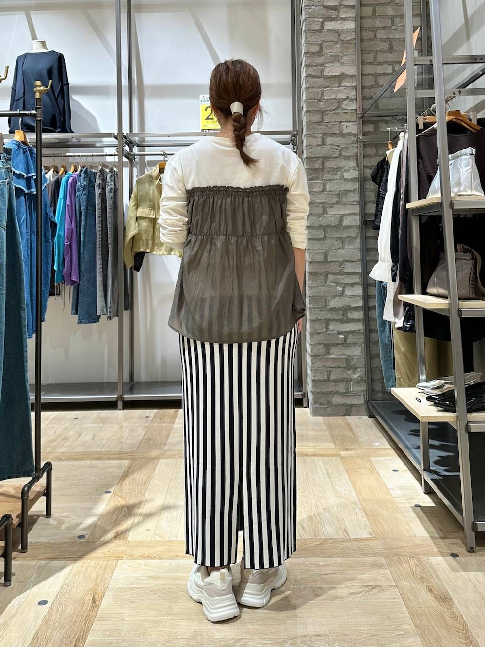 ホワイト系のスニーカー、ブラック系のスカート、グリーン系のTシャツ/カットソーを着用したレディースの秋コーディネートの3枚目の写真