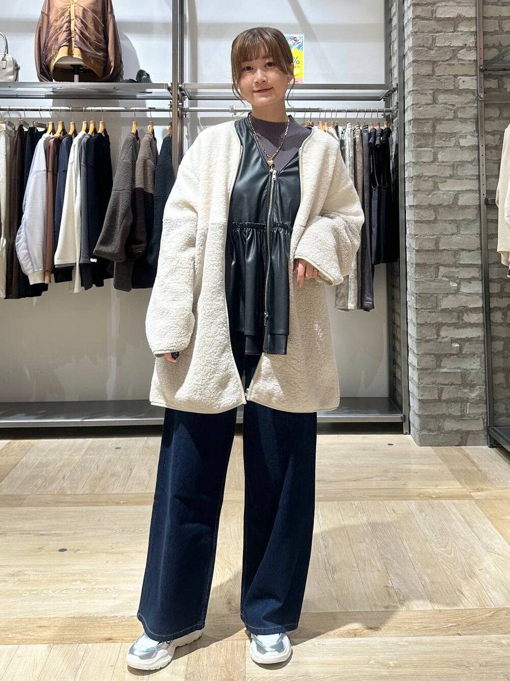 ブルー系のデニムパンツ、グレー系のニット/セーター、ホワイト系のスニーカーを着用したレディースの秋コーディネートの2枚目の写真