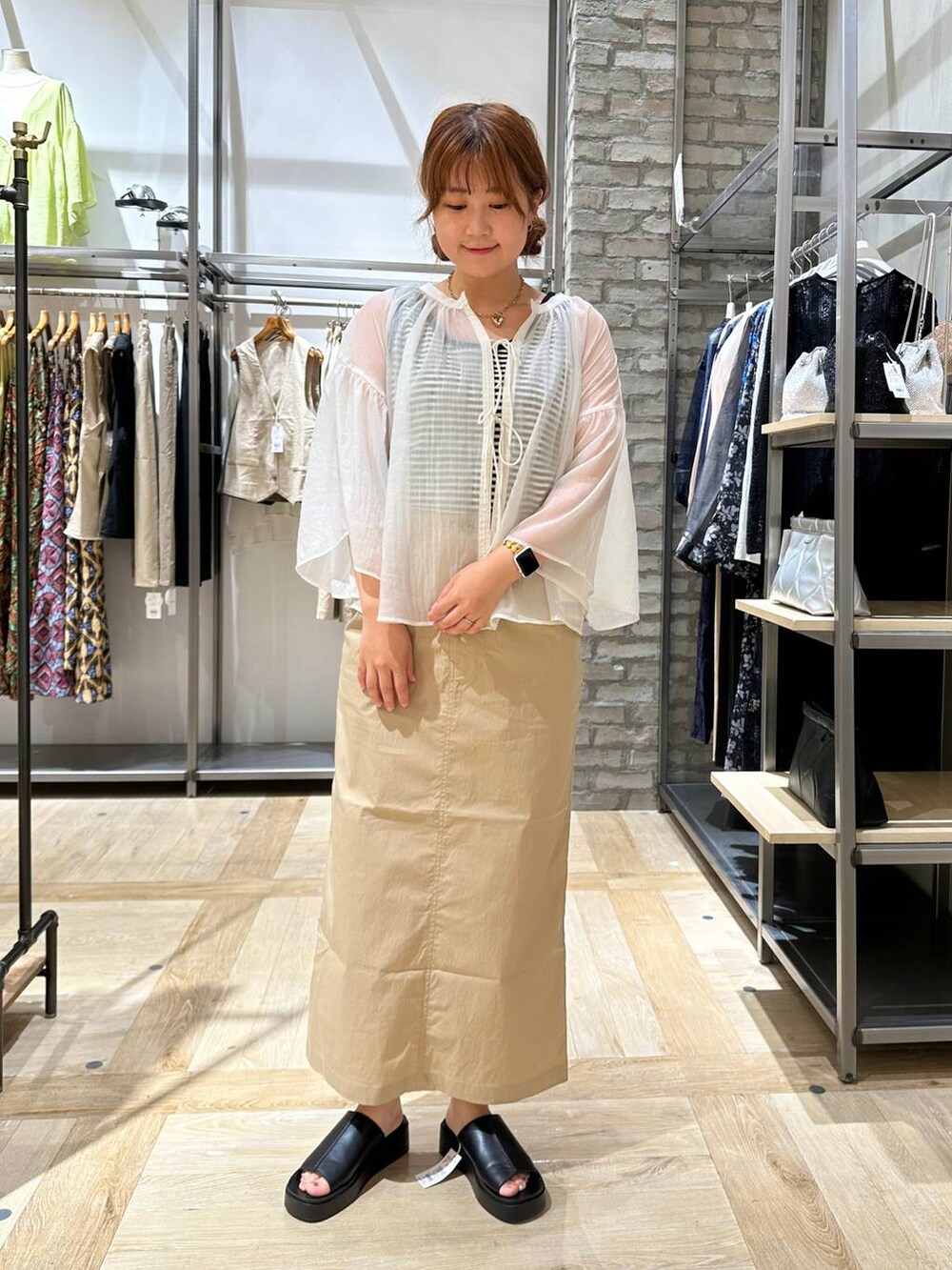 ブラック系のショルダーバッグ、ベージュ系のスカート、ブラック系のサンダルを着用したレディースの夏コーディネートの2枚目の写真