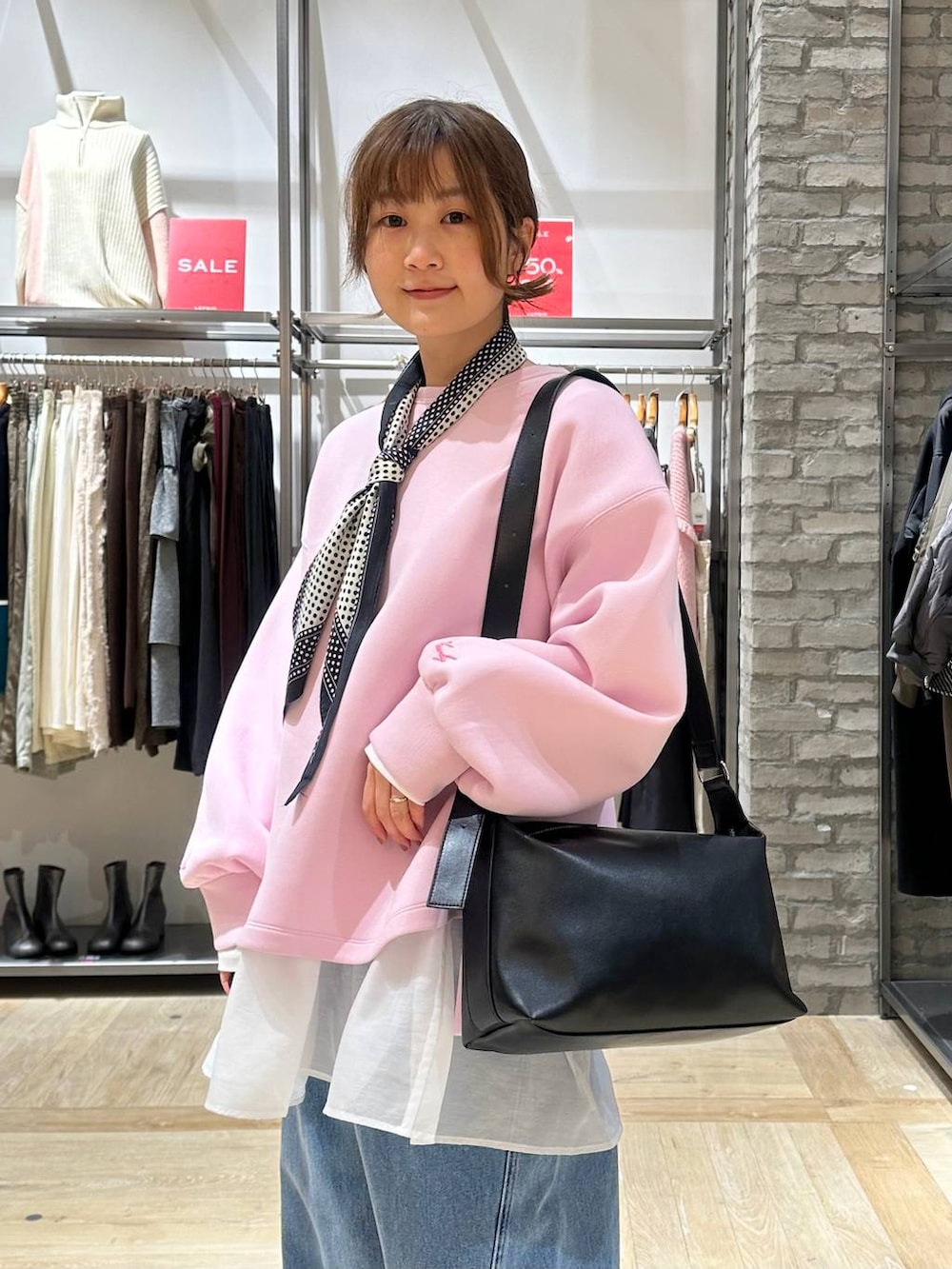 ブラック系のショルダーバッグ、ホワイト系のTシャツ/カットソー、ブラック系のブーツを着用したレディースの冬コーディネートの6枚目の写真